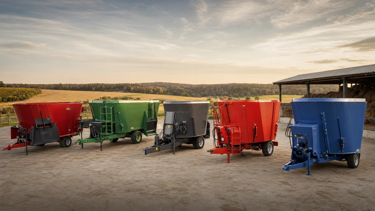 Selbstfahrender Futtermischwagen bei der Ausbringung der TMR-Ration an Milchkühe entlang eines Futtertischs aus Beton in einem modernen, belüfteten Stall.