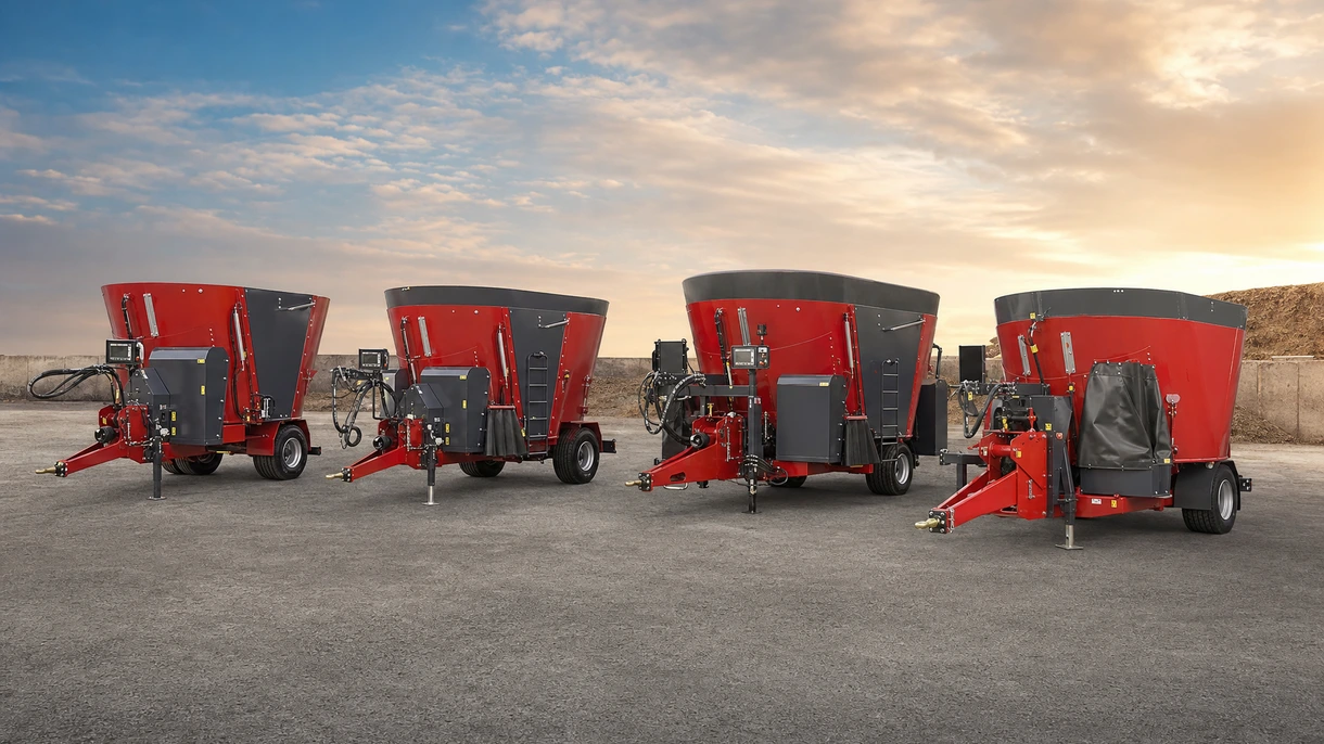 A heavy-duty horizontal mixing wagon discharging a TMR ration into a concrete feed bunk on a modern dairy farm.